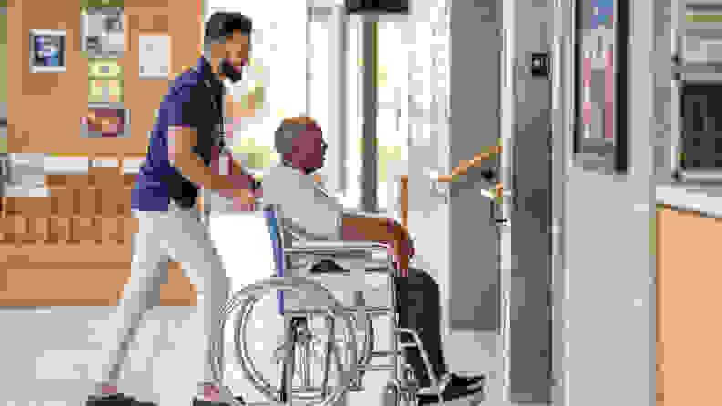 A man pushing a man that's sitting in a wheelchair.