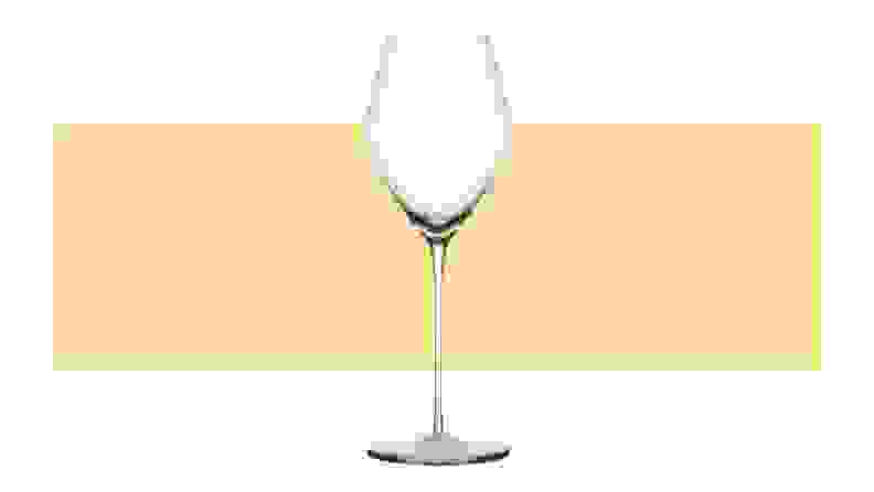 A single dessert wine glass on top a yellow background.