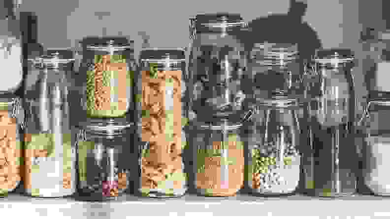 A cabinet full of mason jars house spices, pasta, and nuts.