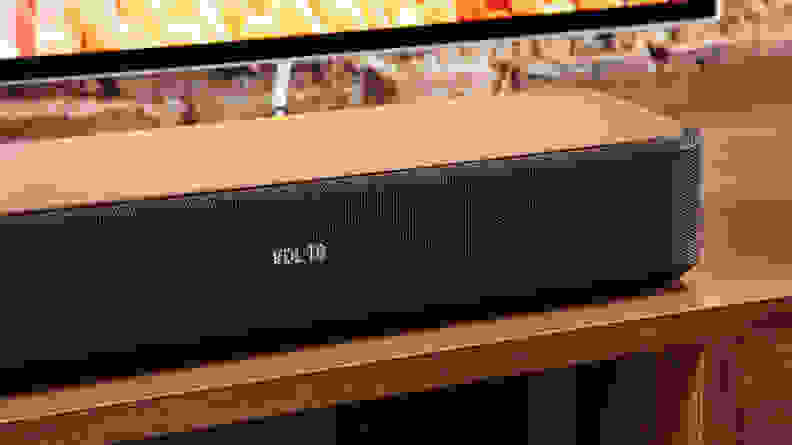 The Sony HT-S2000 soundbar on a wood table next to a TV.
