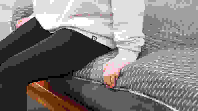 A person sitting on the edge of the Tuft & Needle Mint hybrid mattress.
