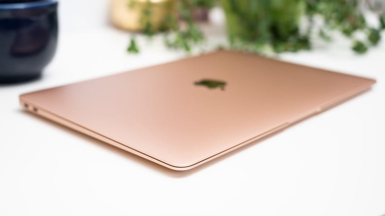 A rose-gold Macbook Air M1 sits shut on a white surface.