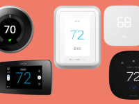 Three black and two white smart thermostats sit on an orange background