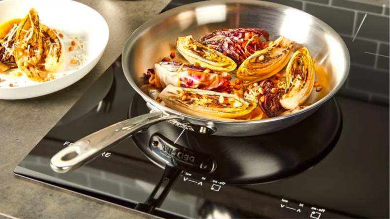 A pan on a stove with cabbages in it.