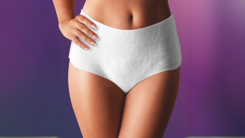 A woman wearing a disposable diaper stands with her hand on her hip
