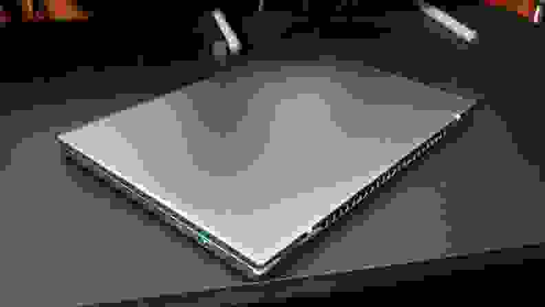 A closed, silver laptop on top of a black desk.