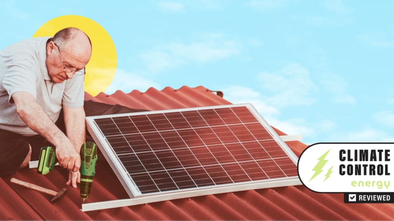 Man using drill to secure solar panel to brown roof against a blue sky.