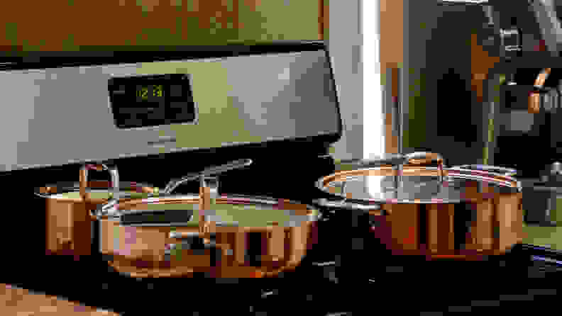 Copper cookware sits on a stovetop.