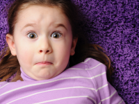 Girl with surprised face laying on purple carpet