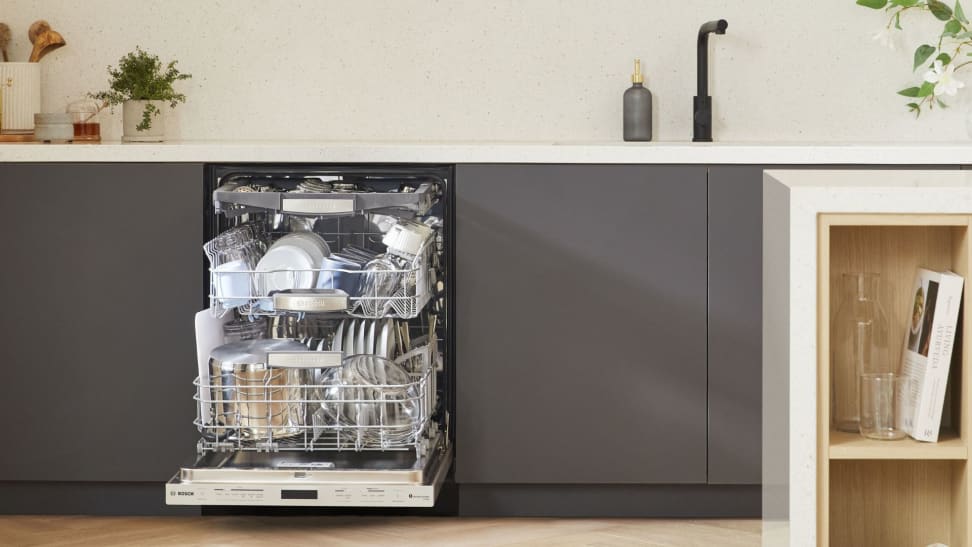 Open Bosch dishwasher, revealing three racks full of dishware, in a modern kitchen
