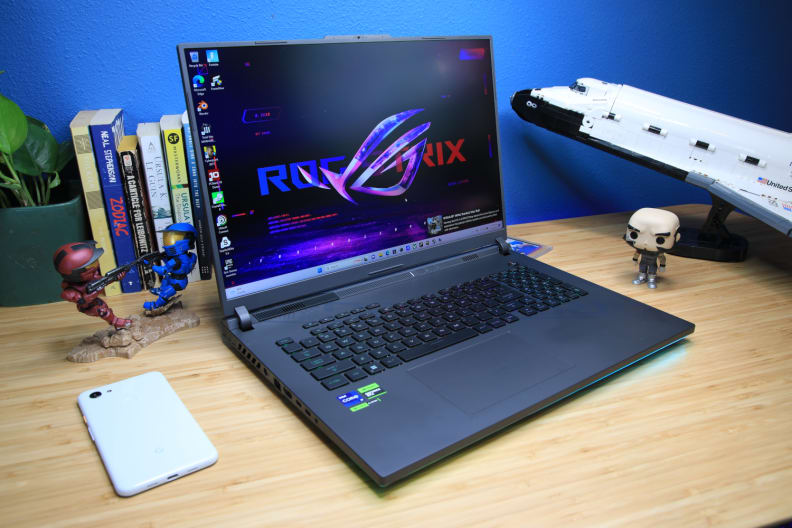 An 18-inch ASUS ROG laptop on a desk between a phone and lego space shuttle