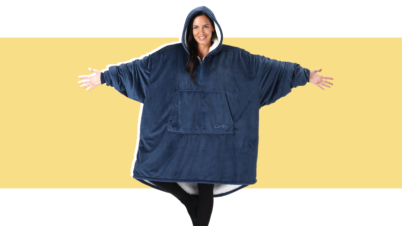 An image of a model wearing the Comfy hoodie in navy blue; the hoodie is oversized and has a white sherpa lined interior.