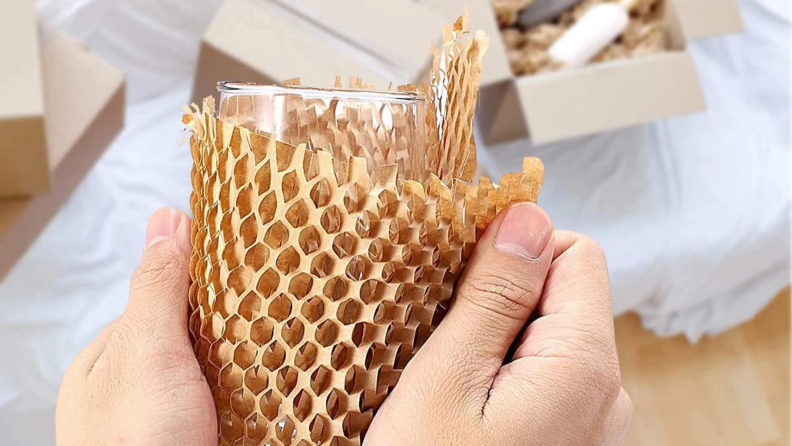 Image of a pair of hands holding a glass wrapped in Besitek Honeycomb Packing Paper.