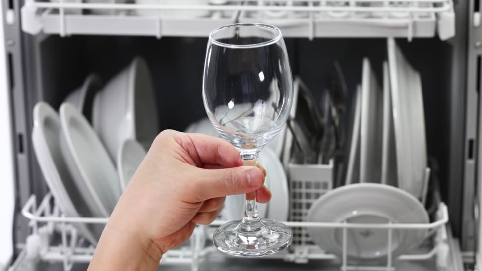Someone examines a wine glass upon taking it out of a high end dishwasher.