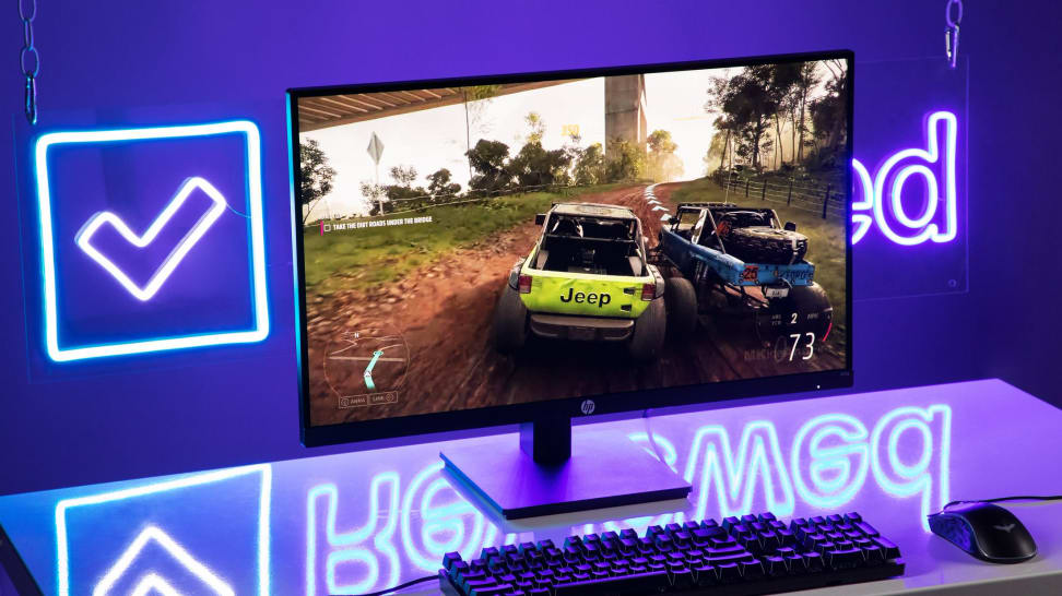 Gigabyte monitor computer on desk in front of blue neon sign that reads "Reviewed."