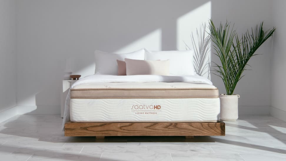 A Saatva mattress sits in a white minimalistic room.
