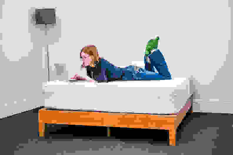 a person lies on their stomach working on their computer on the leesa mattress