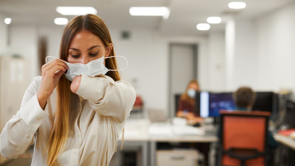 Person with one arm applying face mask to face.