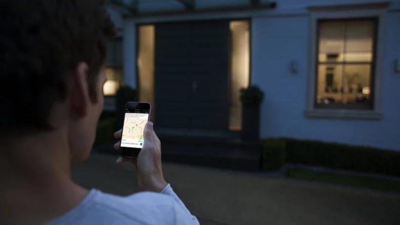 A person outside of their home using the Philips Hue app.