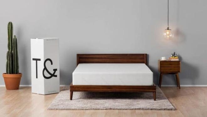Mattress in wooden bed frame in modern bedroom.