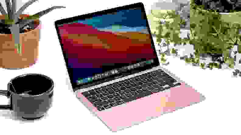 An open laptop surrounded by a mug and plants