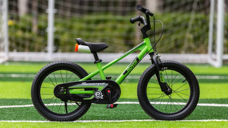 RoyalBaby EZ bike in green sits on a green soccer field in front of a net