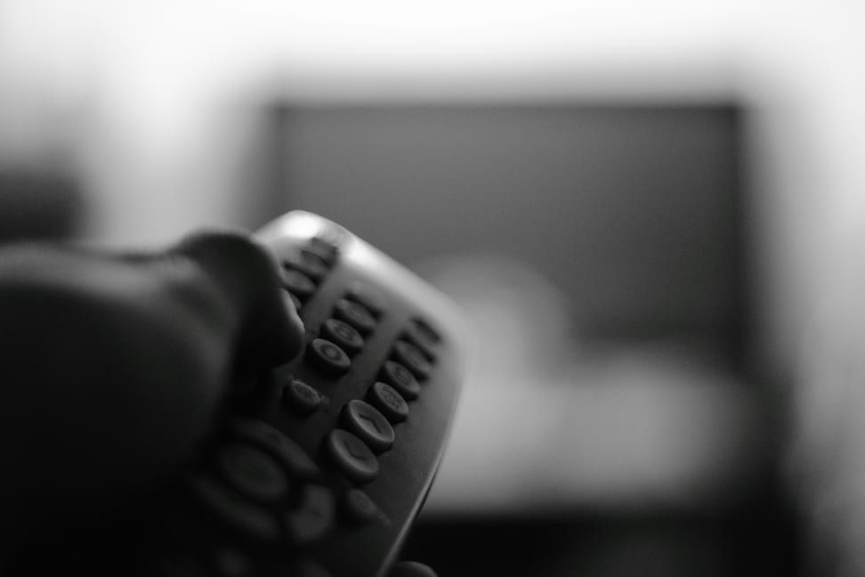 A person points a TV remote at a TV