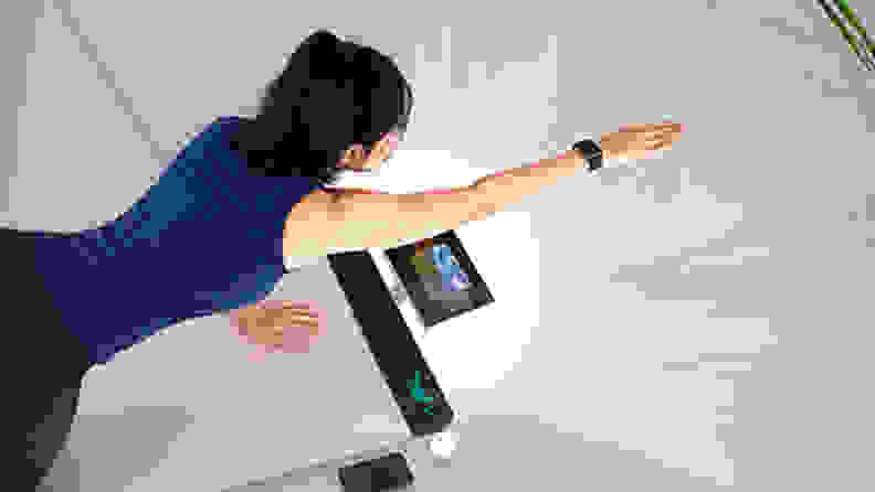 A person practices yoga with the help of the Yogifi smart mat.