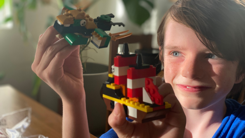 A child holds up their completed Lego builds
