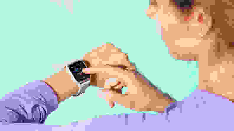 A person taps a Garmin Venu Sq 2 fitness tracker on their wrist.