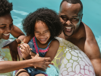 Family of three enjoying fun pool time together with inflatable tube.