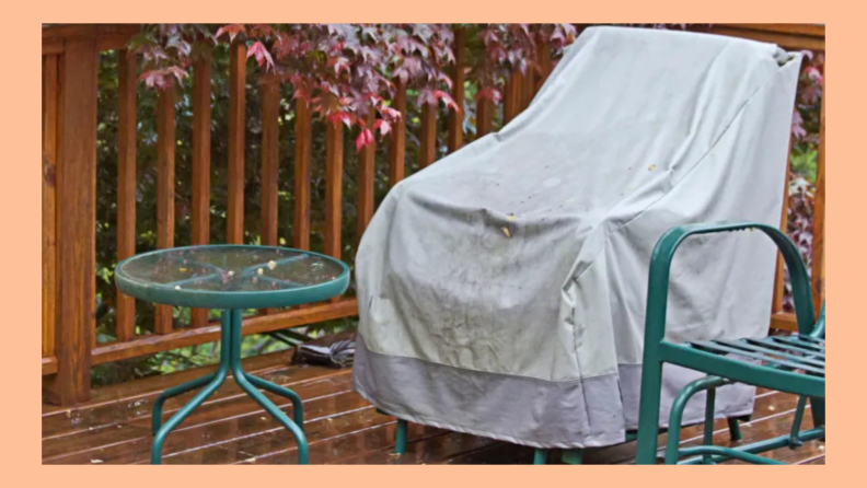 Patio chair covered in a protective patio covering next to a side table on a wet wood deck in the rain