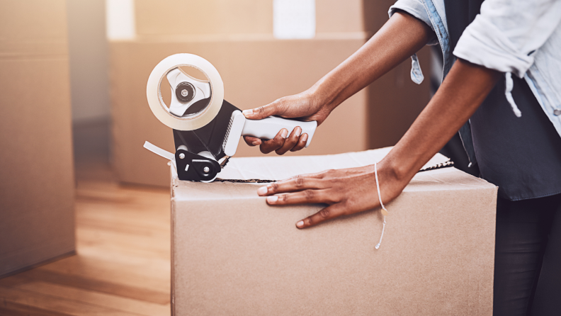 A person taping up a box,