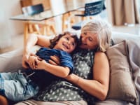 Grandmother and grandson embracing each other on couch at home.