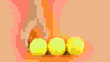 接触在橙色背景的手三个网球。