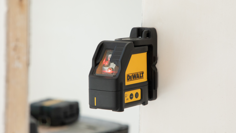 A yellow laser level magnetically attaches to a wall.