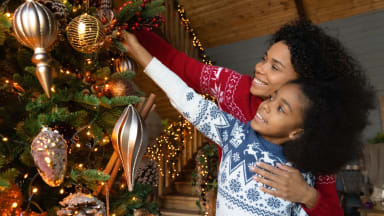 Adult and child decorating a Christmas tree together