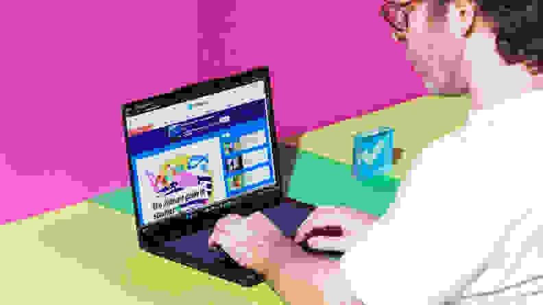 A man typing on a Lenovo Yoga Slim 7x laptop on a pink background.