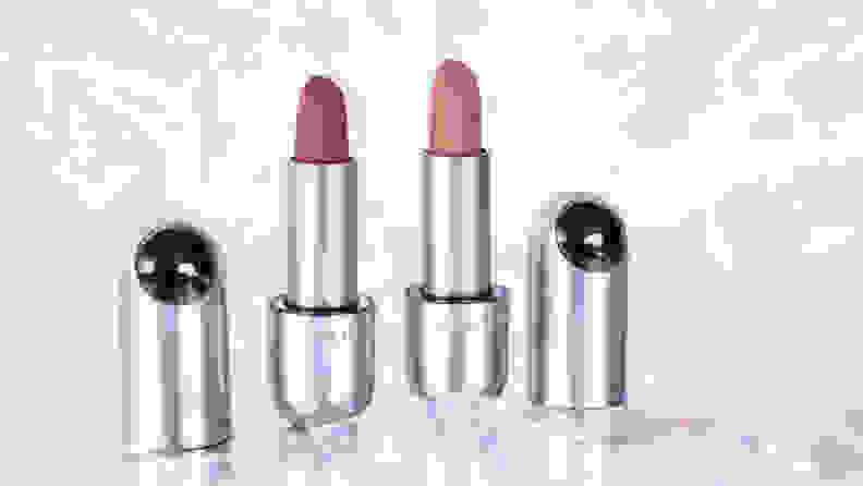 Two lipsticks standing with their caps to the side of them.