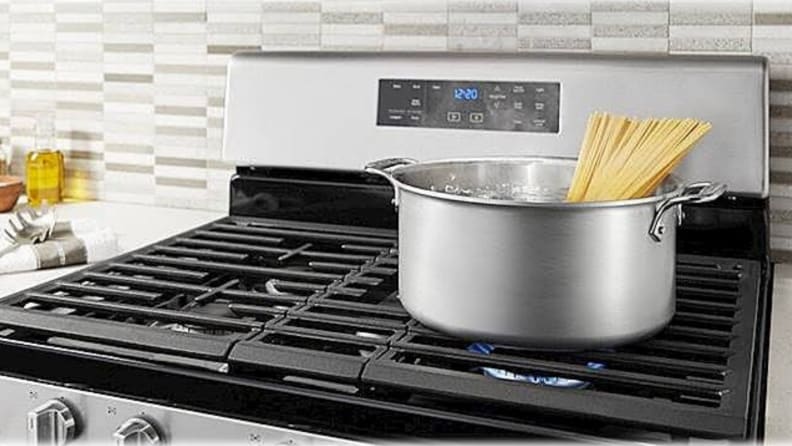 On a black cooktop, a bundle of pasta is getting cooked in a stockpot.