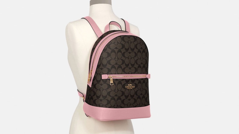 A brown and pink Coach backpack on a mannequin.