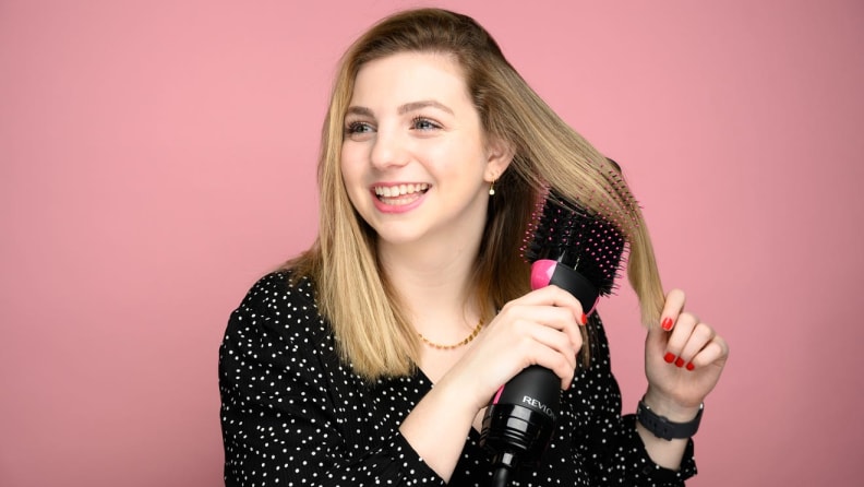 A person brushes their hair with a Revlon product.