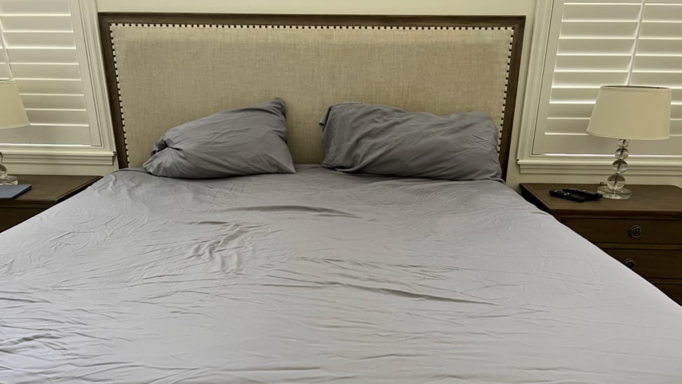 Mattress with gray fitted sheets from Bedsure Bamboo Cooling Sheets and two pillows in front of upholstered headboard.