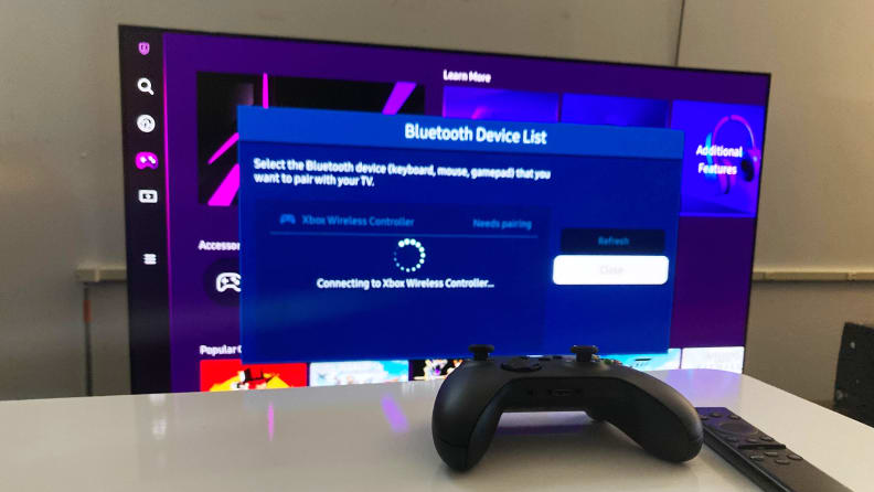Kontroler bezprzewodowy Xbox Series X przed telewizorem Samsung, na którym telewizor wyświetla komunikat o stanie połączenia Bluetooth ze wspomnianą konsolą