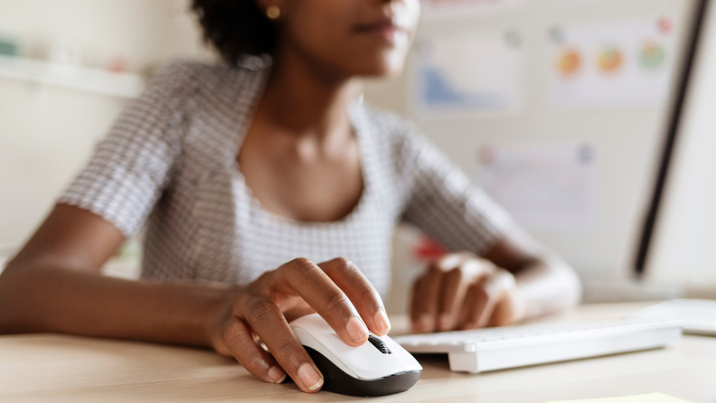 A person using a computer desktop holding a computer mouse.