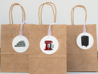 Three brown gift bags on a table with gift tags on them