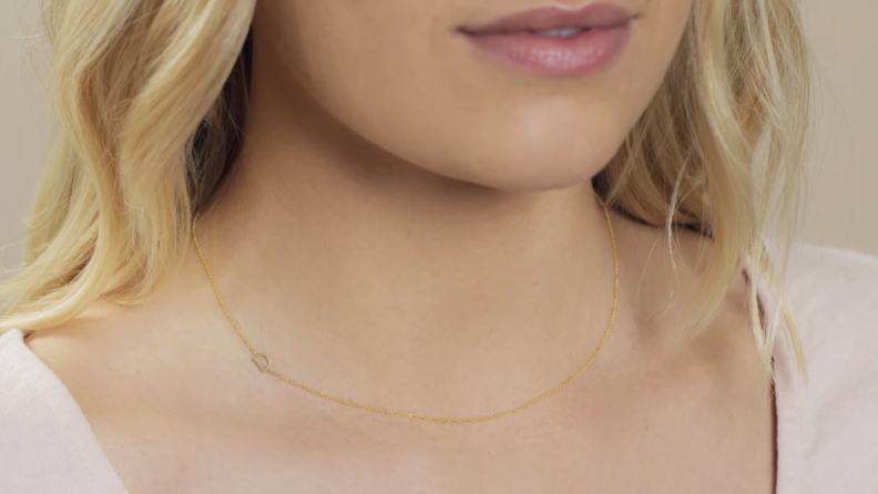 Woman wearing a gold letter 'D' necklace