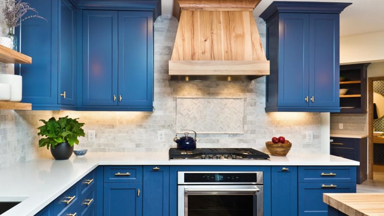 Kitchen with cabinets painted blue, and white countertops.