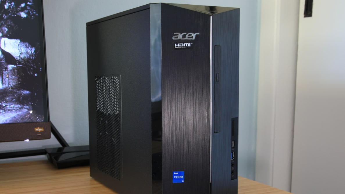 A black Acer desktop computer tower sits on top of a desk next to a computer monitor.