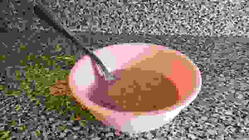 A pink bowl of frozen shaved fruit on a marble countertop.